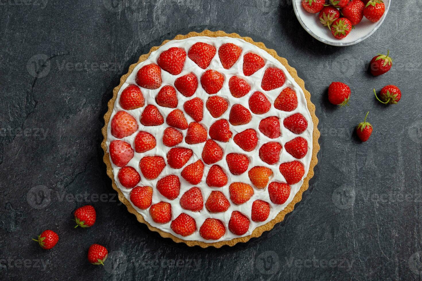 Delicious strawberry tart with whipped cream and mascarpone on a dark concrete background. Top view. photo