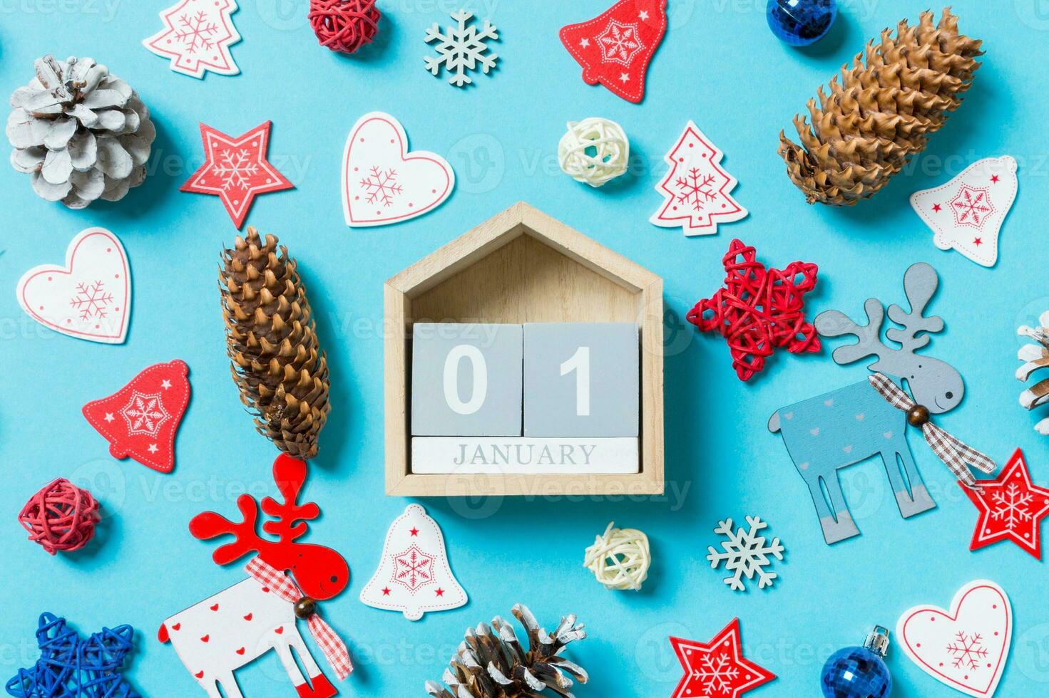 Top view of wooden calendar surrounded with New Year toys and decorations on blue background. The first of January. Christmas time concept photo