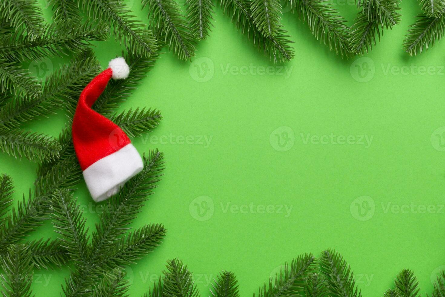 Christmas holiday composition. fir branches with santa hat on green background. New Year, winter concept. Flat lay, top view, copy space photo