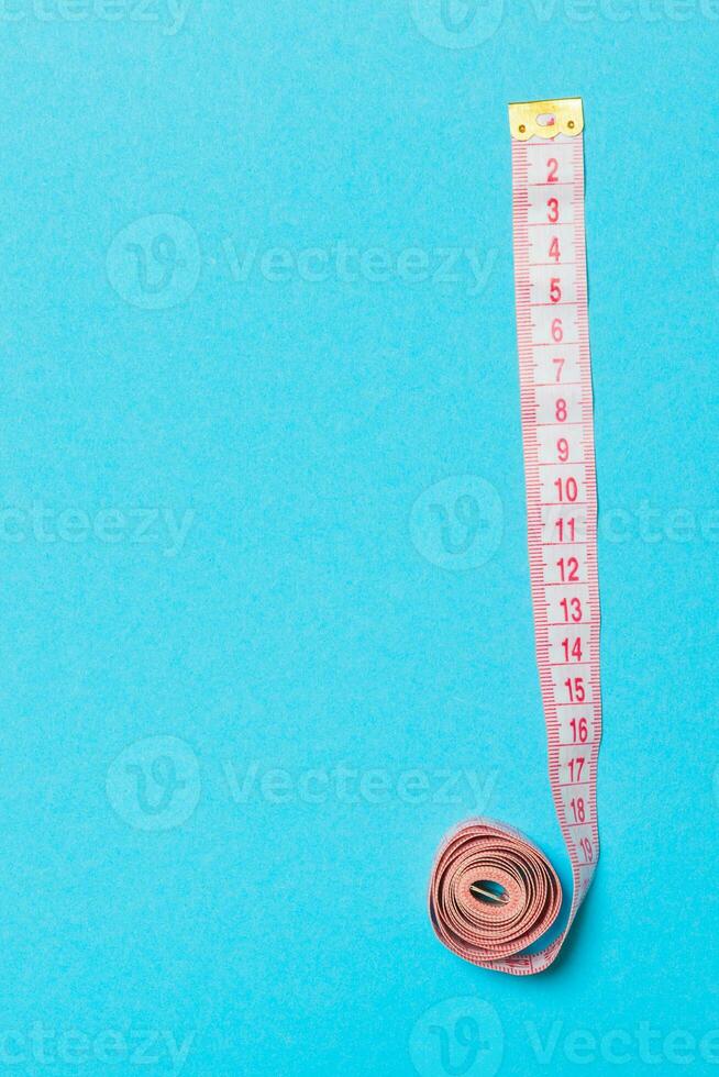 Frame made of measuring tape on blue background. Top view of sewing concept. Slim waist concept with empty space for your design photo