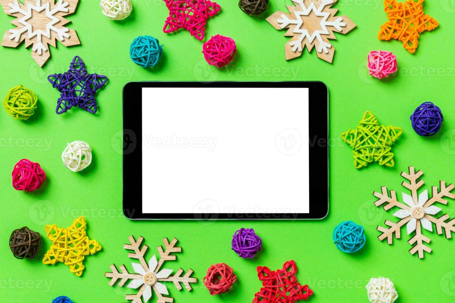 Top view of digital tablet. New Year decorations on green background. Festive stars and balls. Merry Christmas concept photo