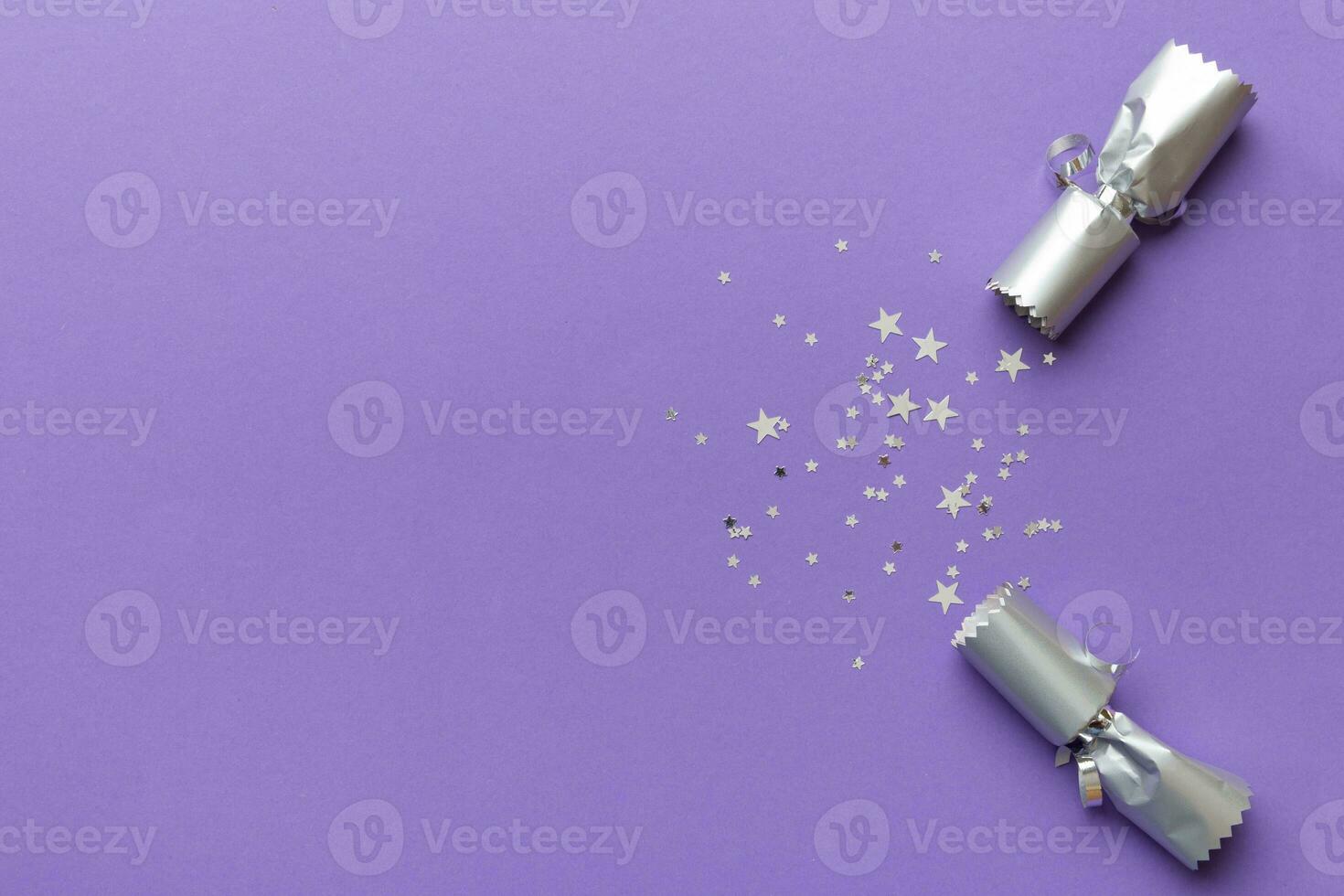 Christmas crackers with shiny confetti on color background, top view, copy space photo
