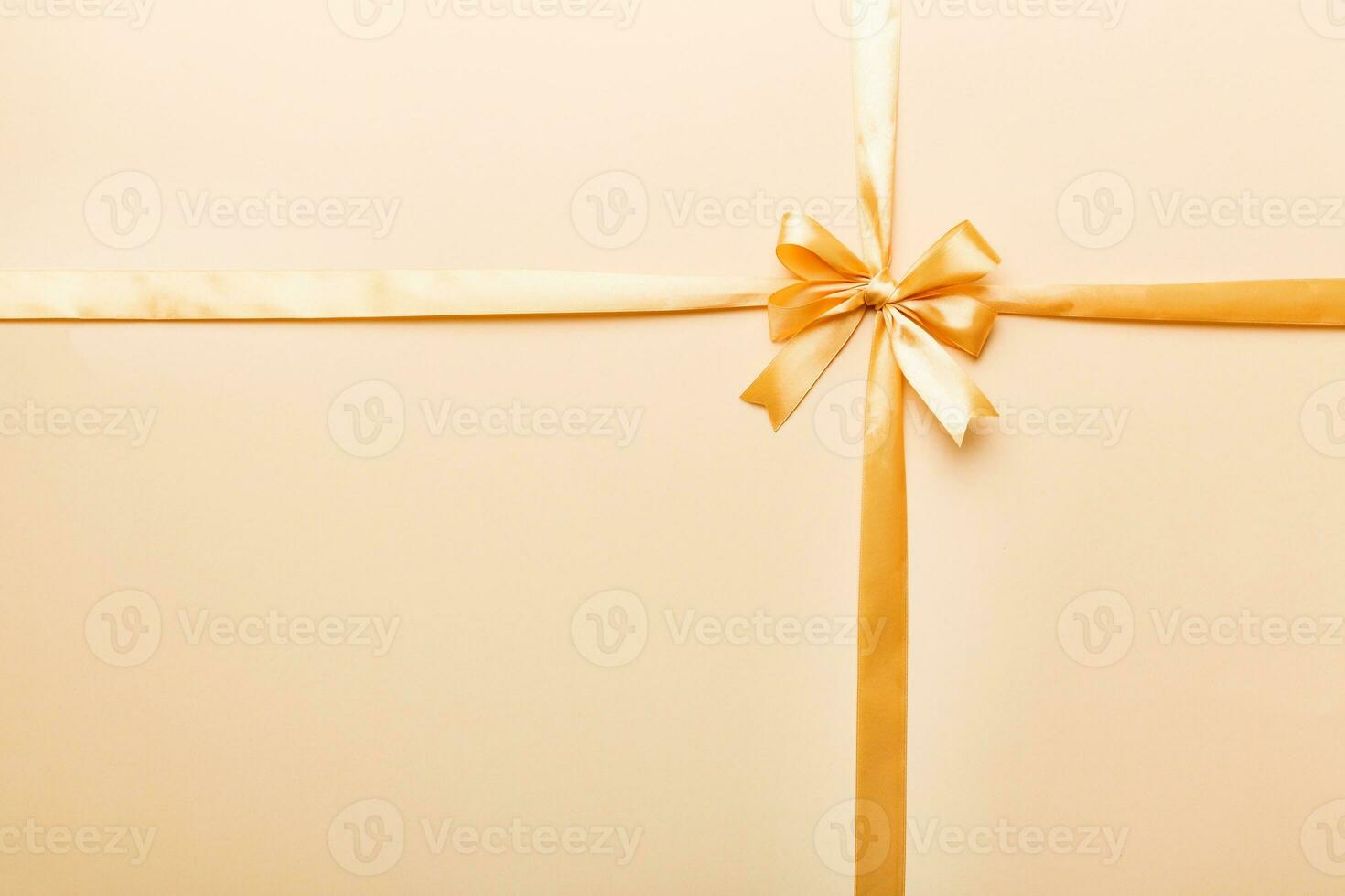 Top view of gold ribbon rolled and yellowbow isolated on colored background. Flat lay with copy space photo