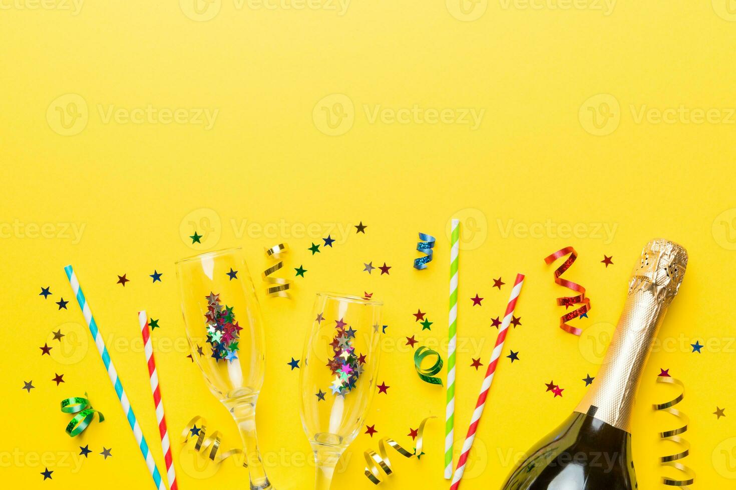 bottle of champagne with glasses and colorful confetti on colored background. top view flay lay photo