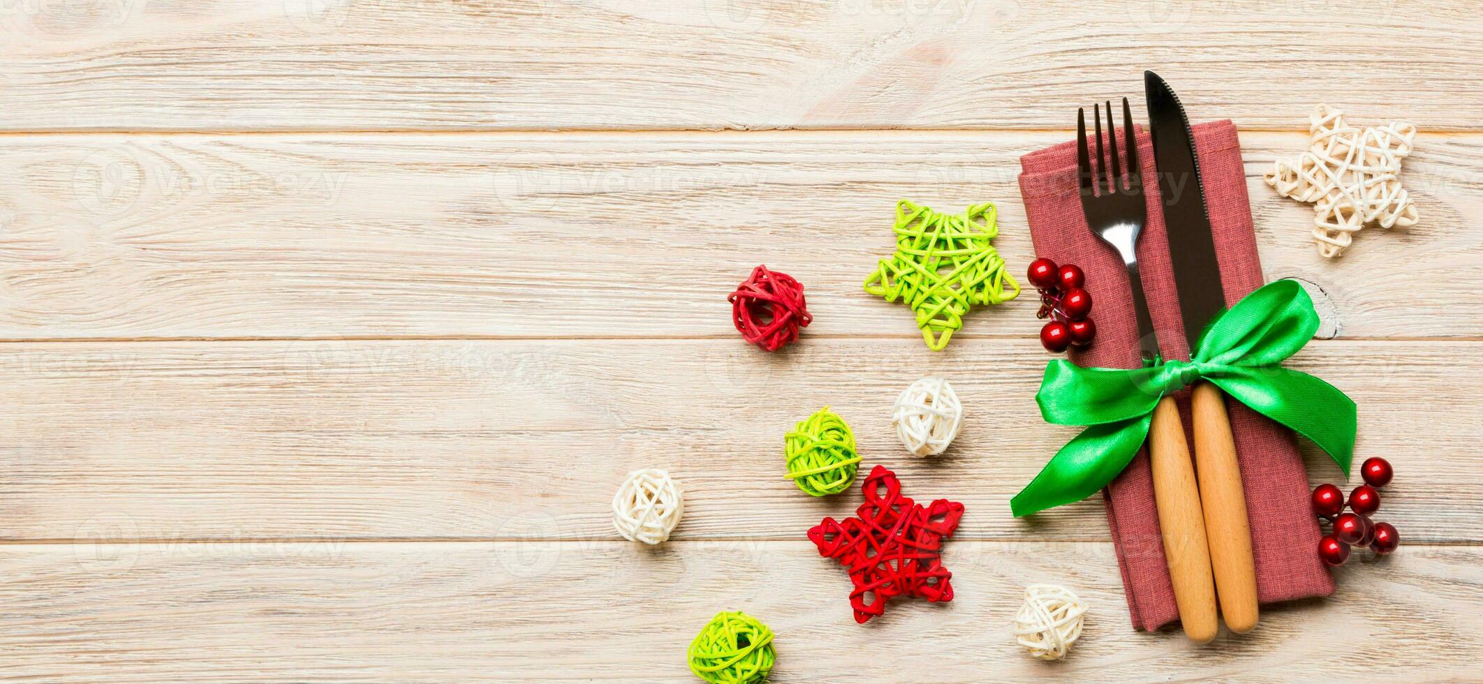 Banner top view of holiday set of fork and knife on wooden background. Christmas decorations and toys with copy space. New Year Eve concept photo