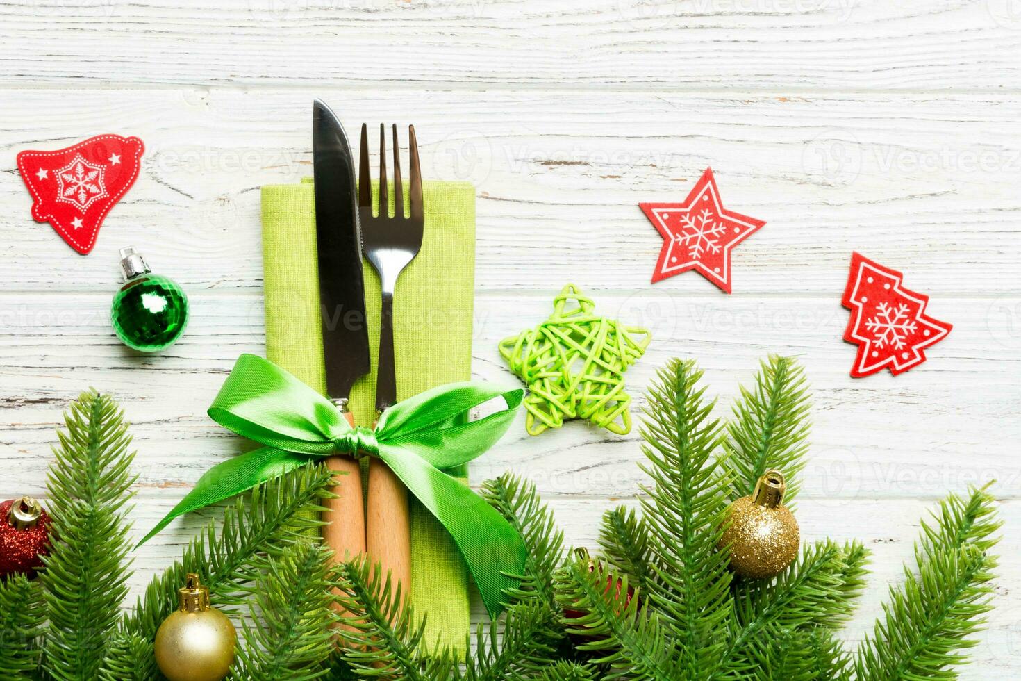 Top view of christmas decorations on wooden background. Fork and knife on napkin tied up with ribbon and empty space for your design. New year pattern concept photo