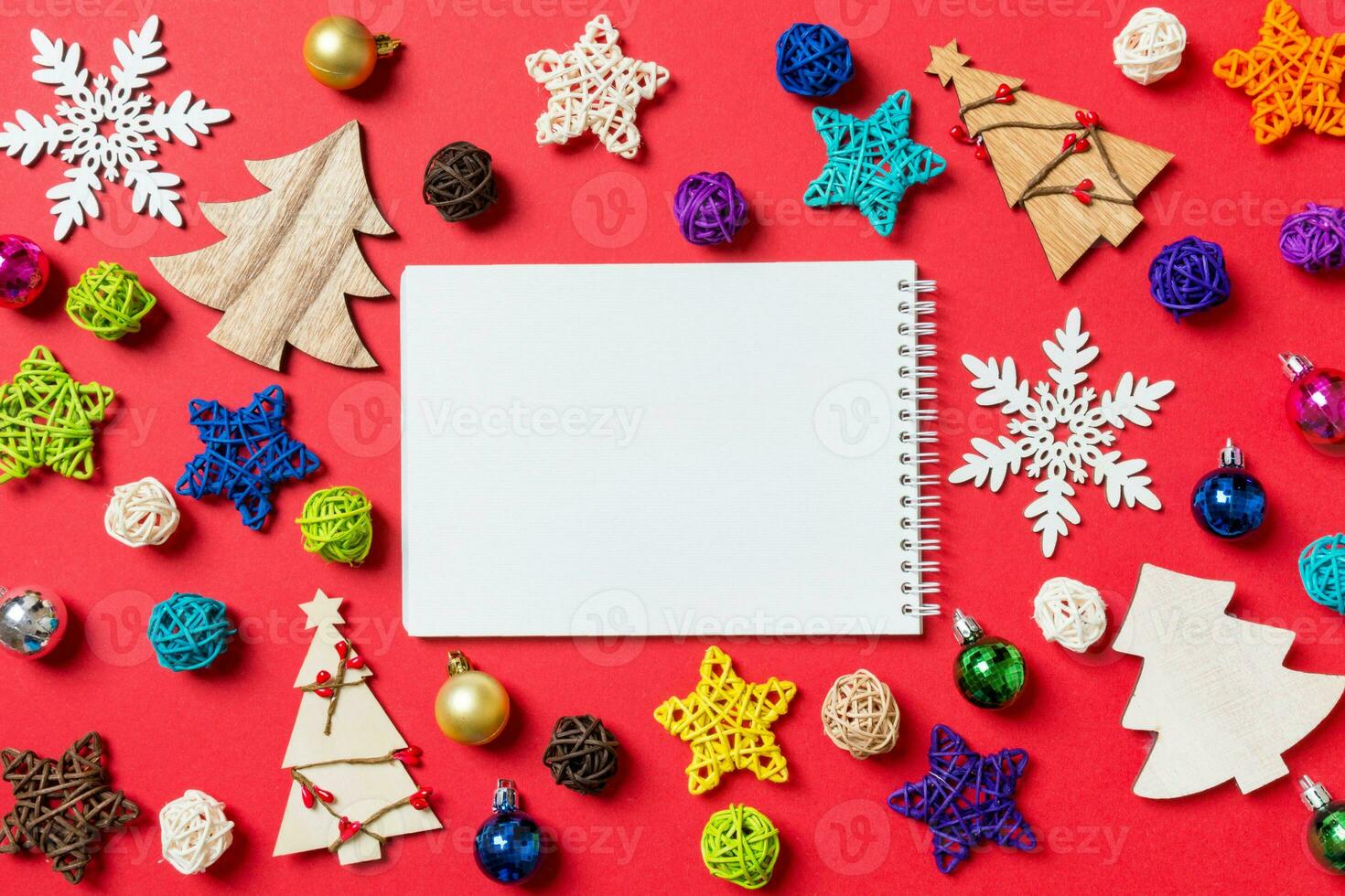 Top view of notebook on red background made of holiday decorations and toys. Christmas ornament concept photo