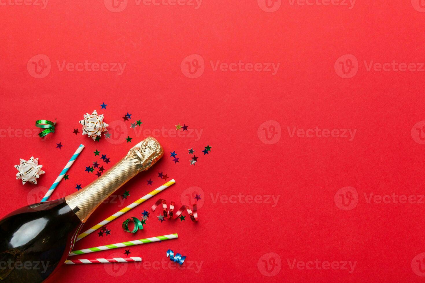 bottle of champagne with glasses and colorful confetti on colored background. top view flay lay photo