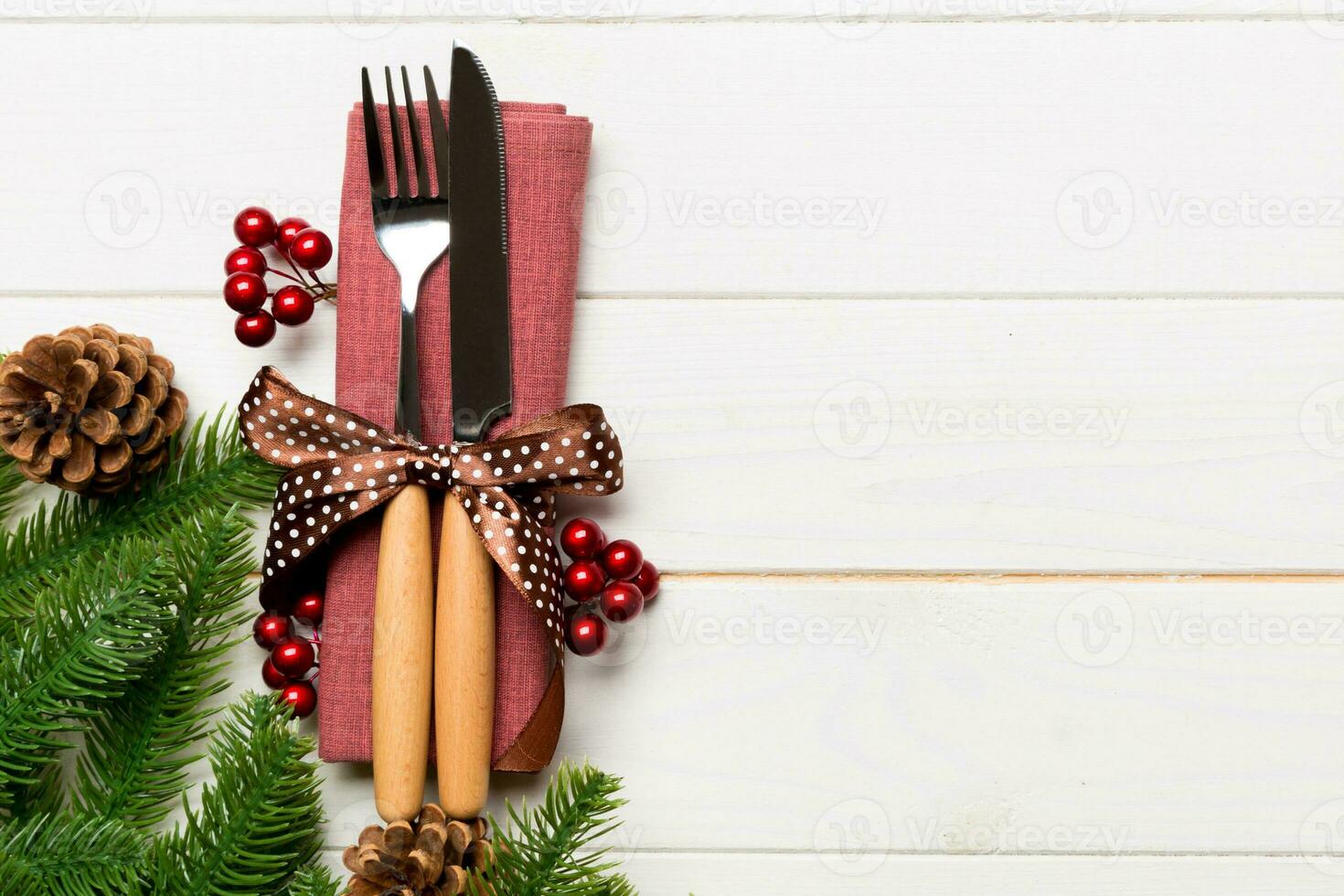 Top view of christmas decorations on wooden background. Fork and knife on napkin tied up with ribbon and empty space for your design. New year pattern concept photo
