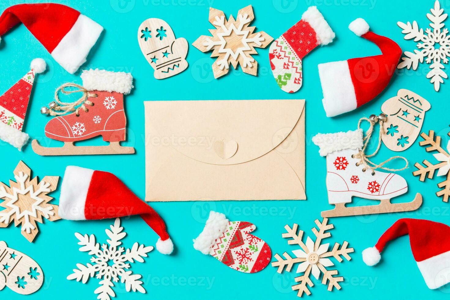 Top view of craft envelope with Christmas decorations and Santa hats on blue background. Happy holiday concept photo