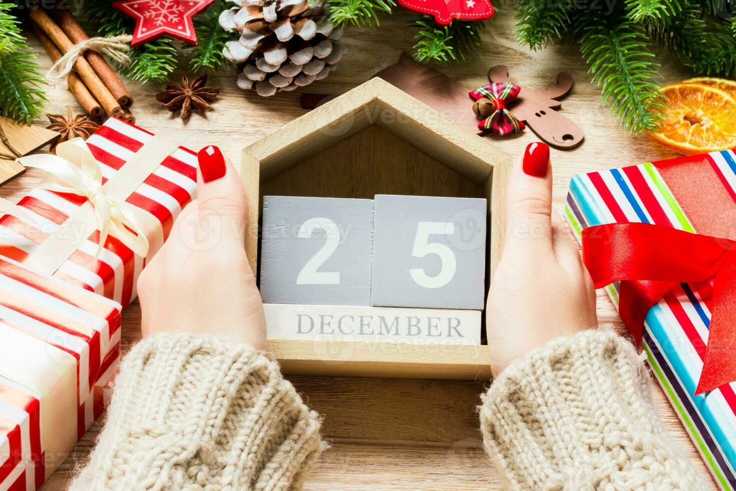 Top view of female hands holding a calendar on wooden background. The twenty fifth of December. Holiday decorations. Christmas concept photo