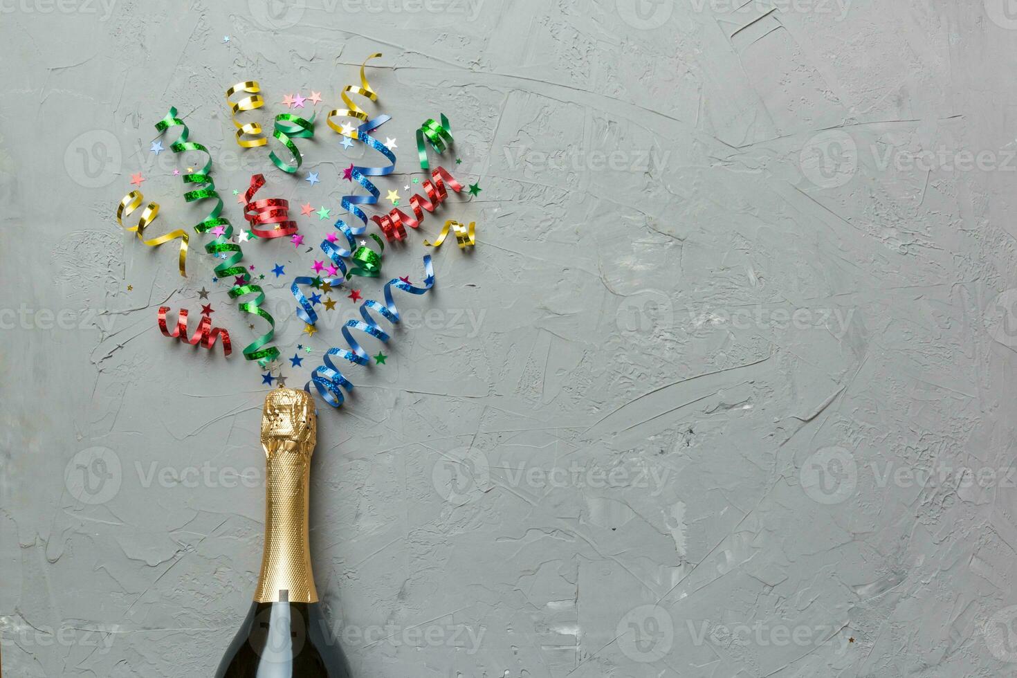 Creative flat lay composition with bottle of champagne and space for text on color background. Champagne bottle with colorful party streamers. holiday or christmas concept photo