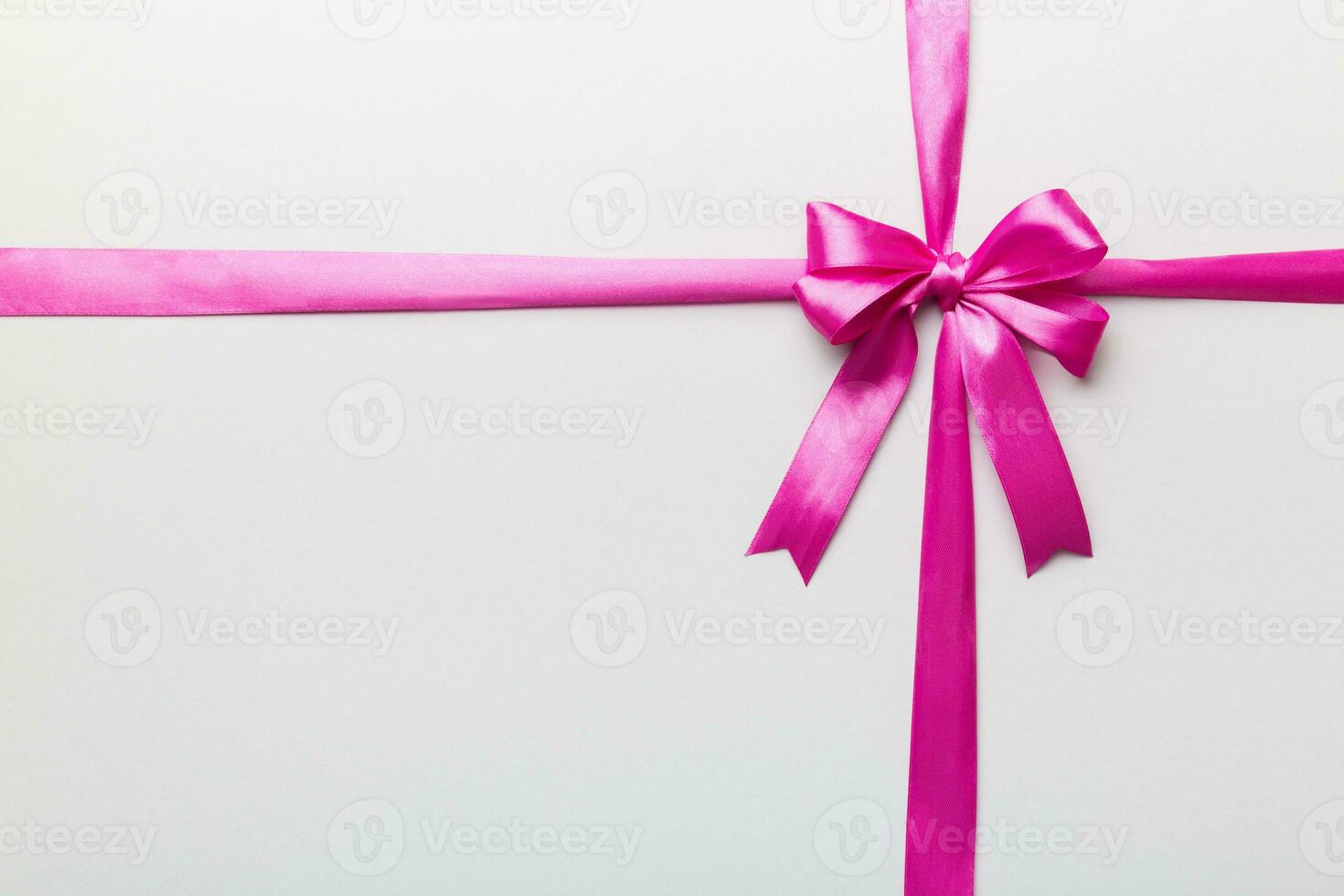 Top view of purple ribbon rolled and pink bow isolated on colored background. Flat lay with copy space photo