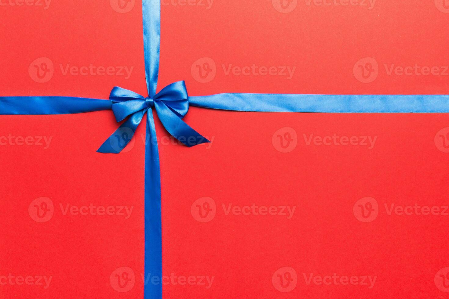 Top view of blue ribbon rolled and blue bow isolated on colored background. Flat lay with copy space photo