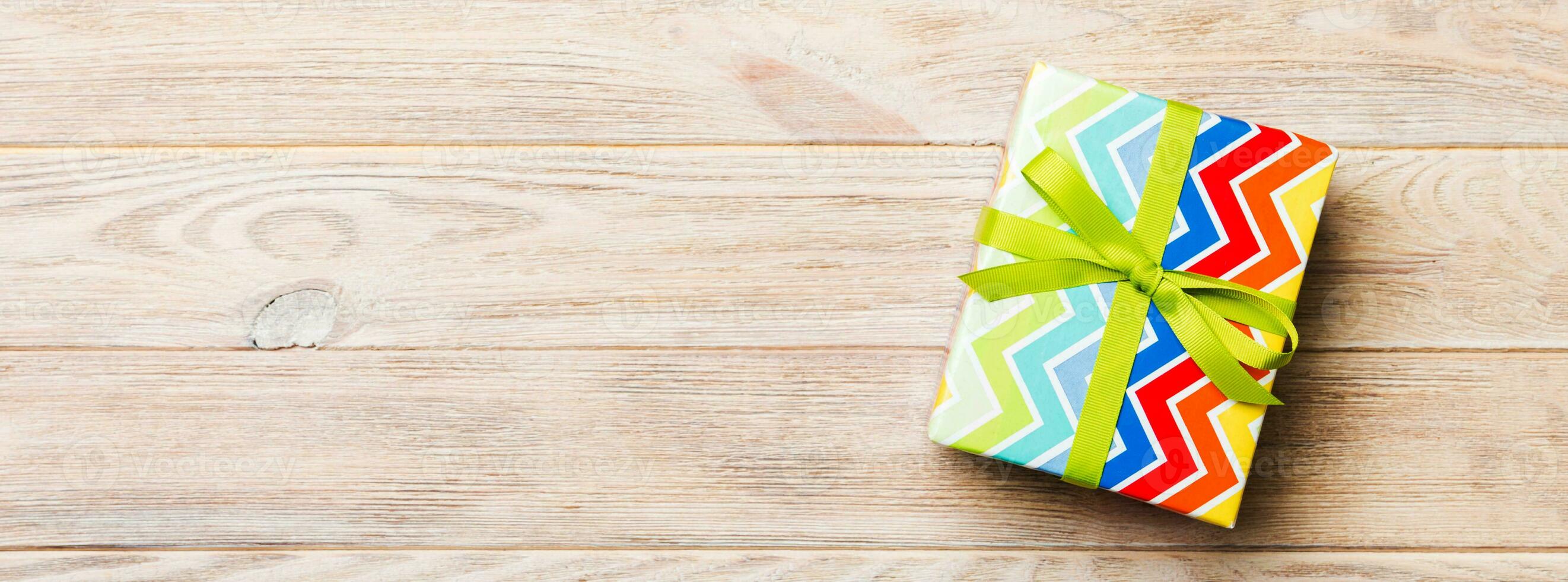 Beautiful gift box with a colored bow on the yellow wooden table. Top view banner with copy space for you design photo