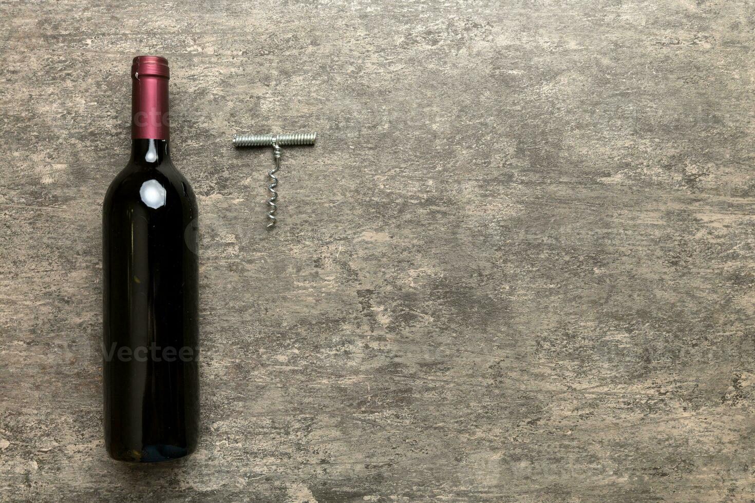 One Bottle of red wine with corkscrew on colored table. Flat lay, top view wth copy space photo