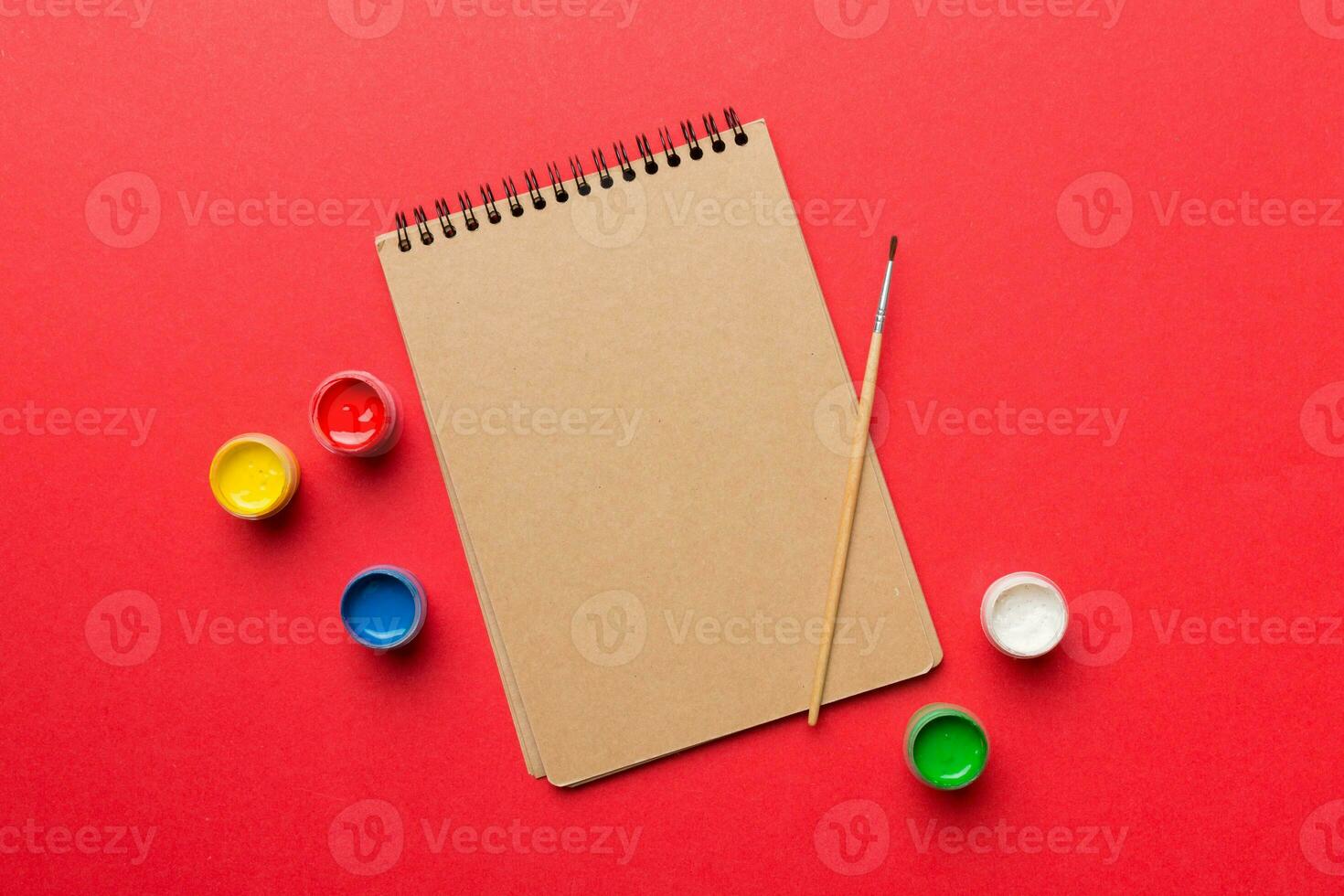 Album pages and paints, pencils, brush on a colored background. Top view with empty space. workplace for creativity. home teaching concept drawing photo