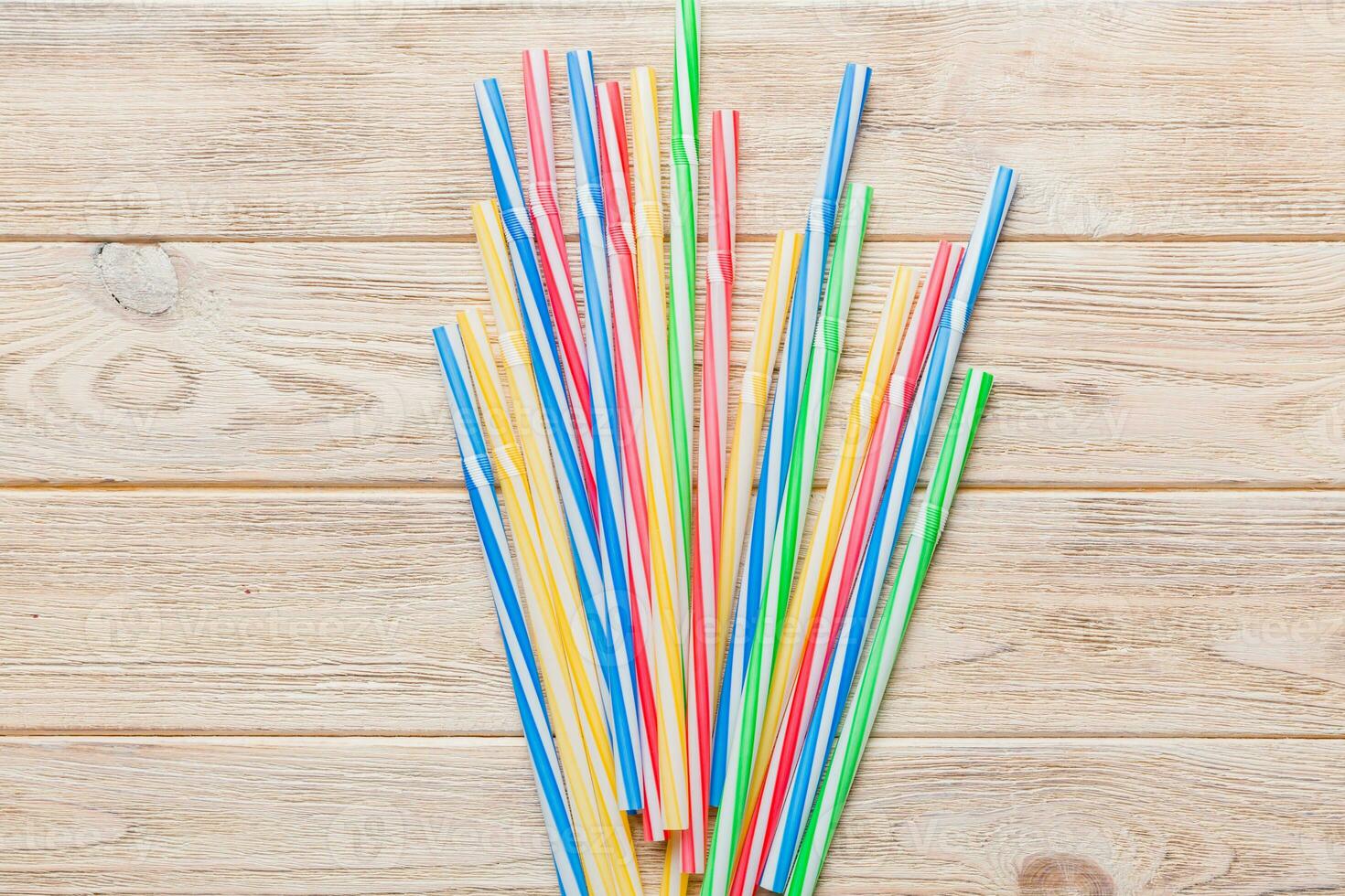 many multi-colored plastic tubes for cocktail on Colored background, top view photo