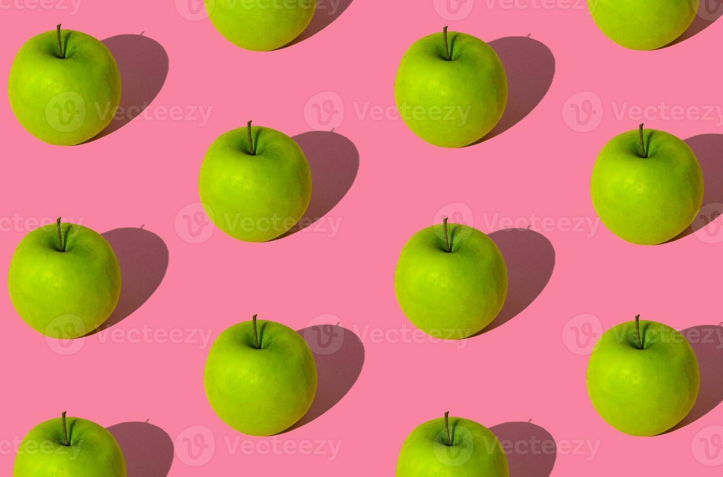 Trendy fruit pattern made of green apples on light pastel pink background. Minimal layout. Nature summer concept. photo