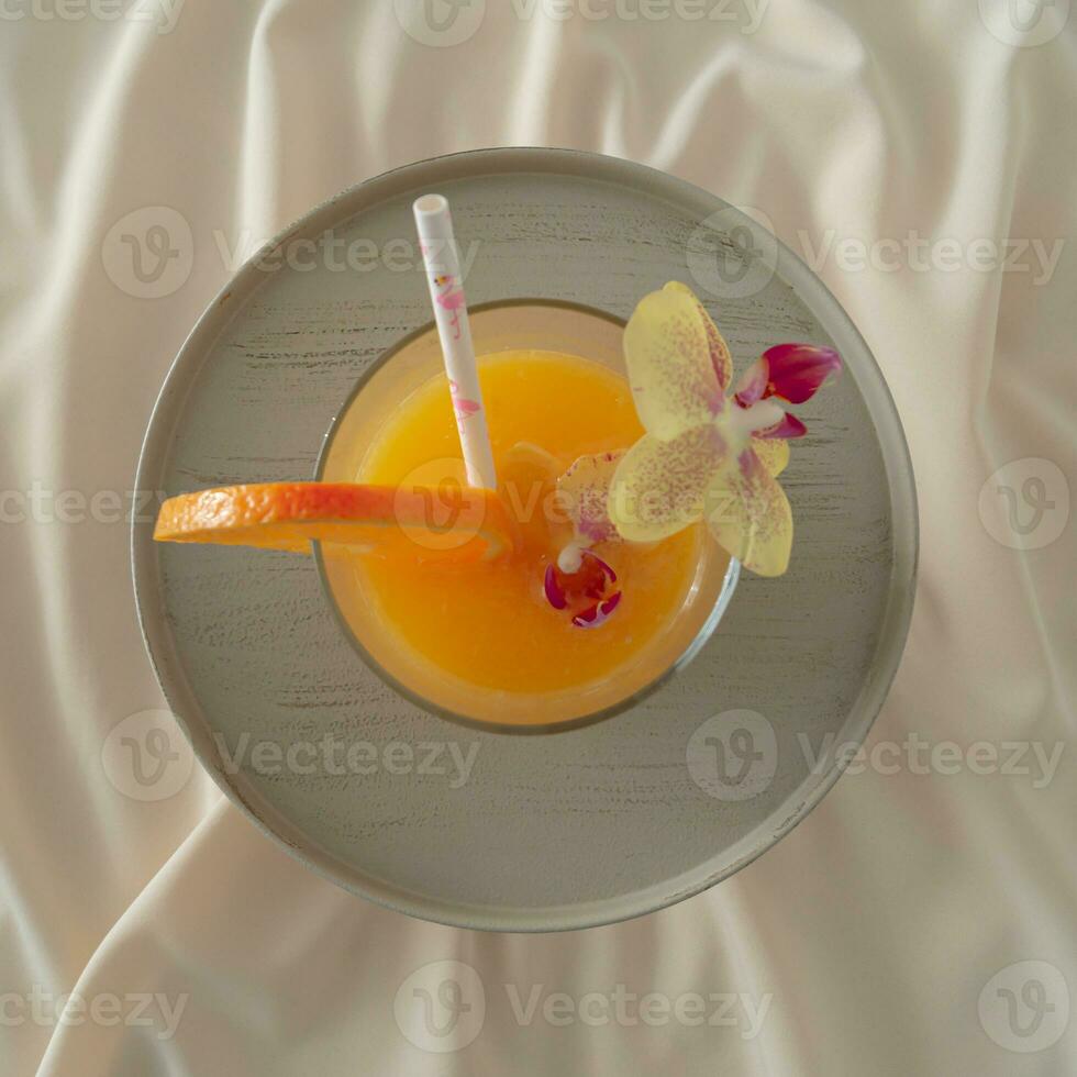 Summer tropical orange juice cocktail on sandy silk background. Minimal summer drink composition. Fruit cocktail flat lay idea. photo