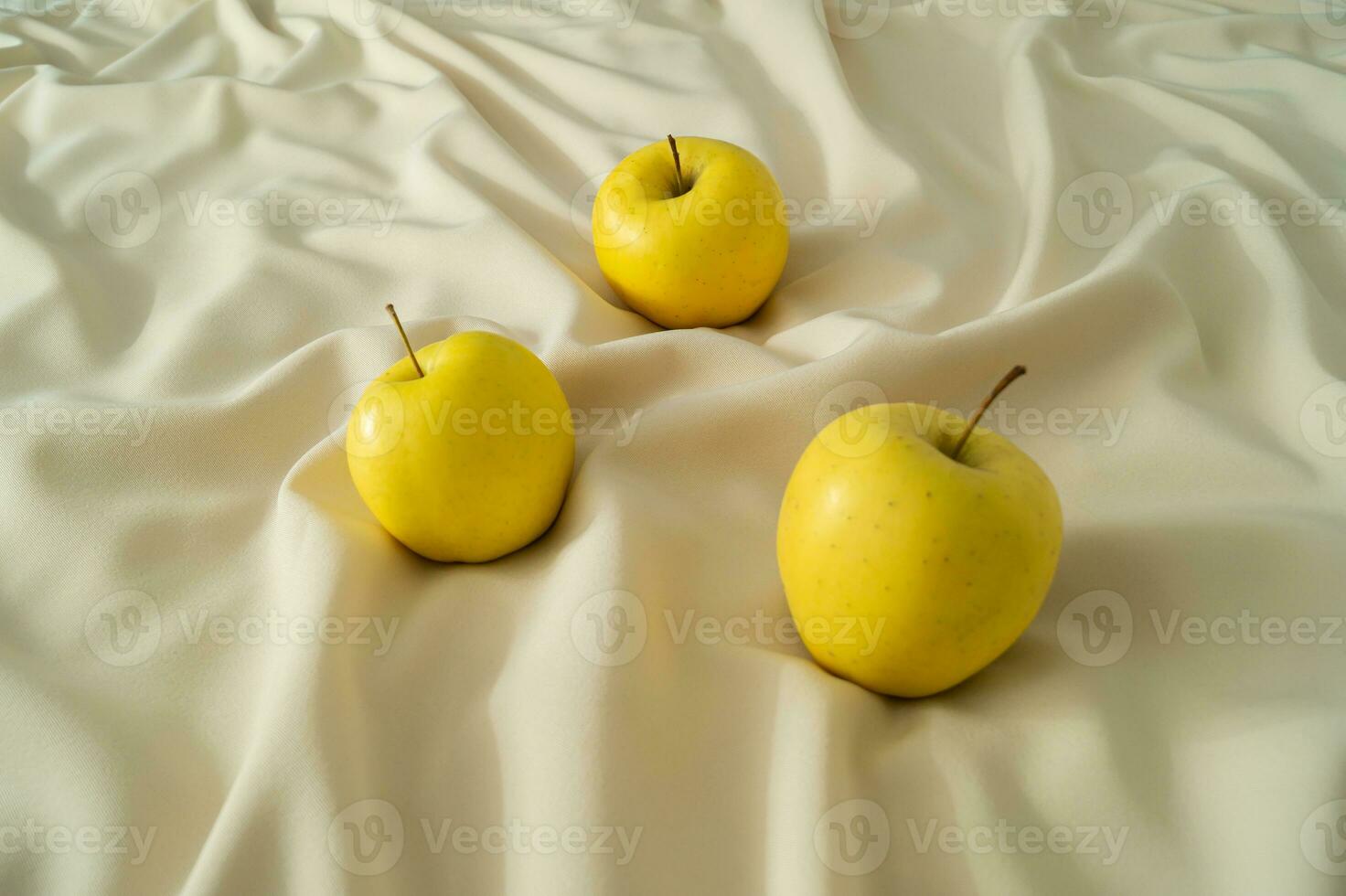 Yellow organic apples on luxury sandy silk. Healthy food idea. Minimal creative concept of simplicity. photo
