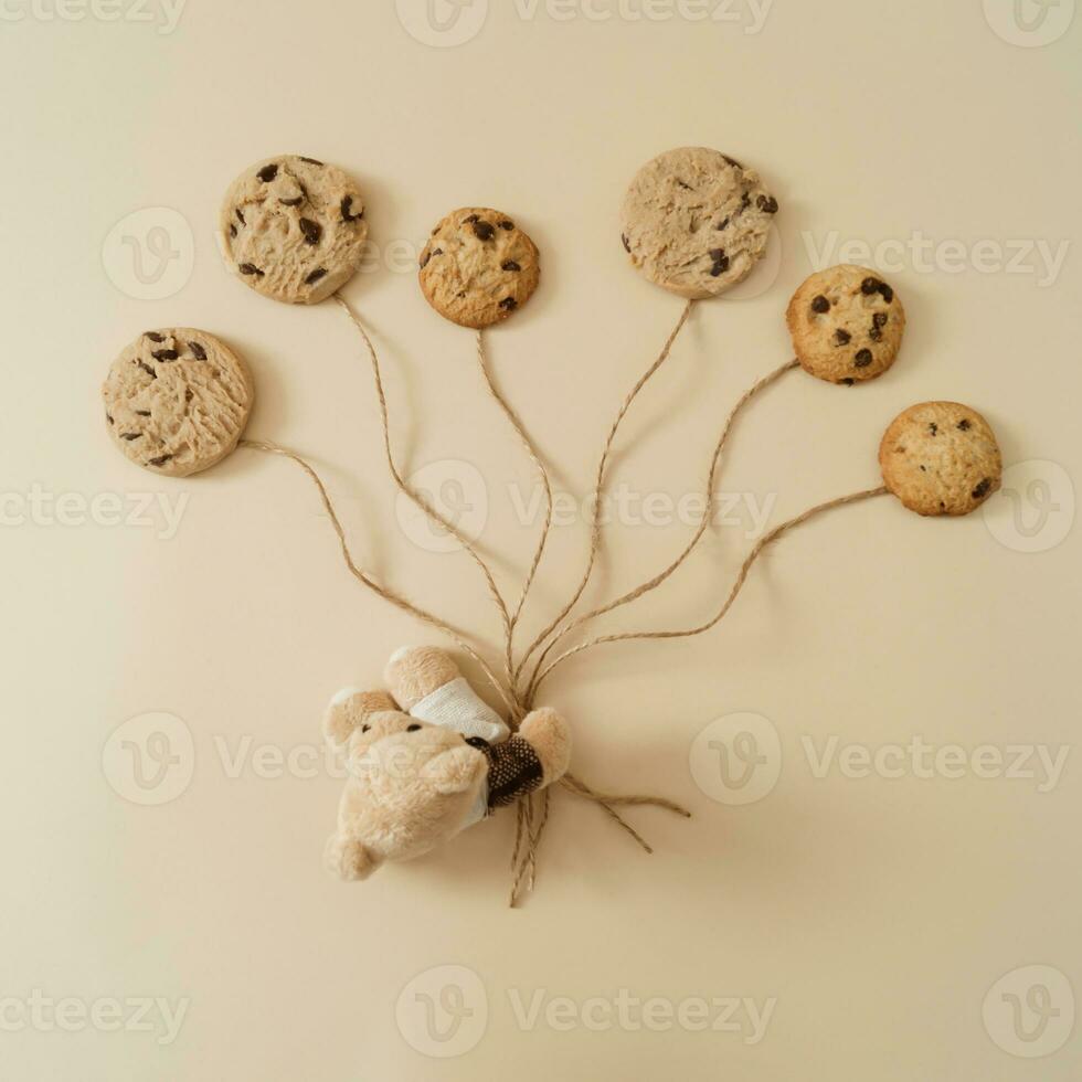 Teddy bear with chocolate cookies balloons on pastel cream background. Minimal sweet concept. Creative cookie idea. Trendy chocolate cookies layout. Flat lay, top of view. photo