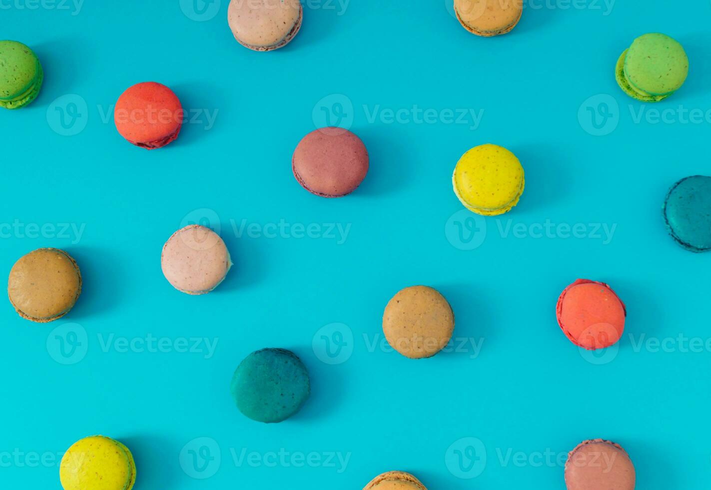 Creative colorful pattern made of various macarons on bright blue background. Minimal sweet food concept. Trendy macaron cookies pattern background. Yummy flat lay idea. photo