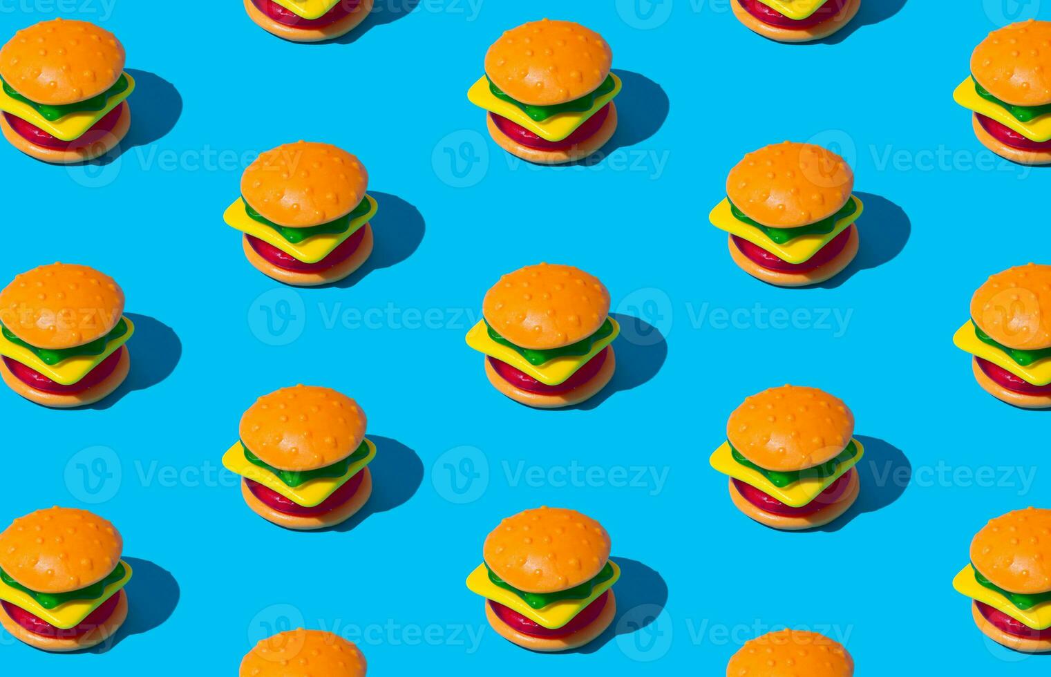Creative pattern composition of big burger made of colorful gummy candies on blue background. Minimal food concept. Tasty jelly sweets idea. Gummy candies aesthetic. photo