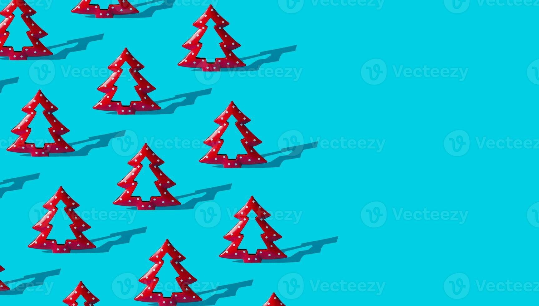 Minimal composition pattern background of red Christmas trees on light blue with copy space. New Year or Christmas concept. Trendy winter holidays pattern background idea. photo