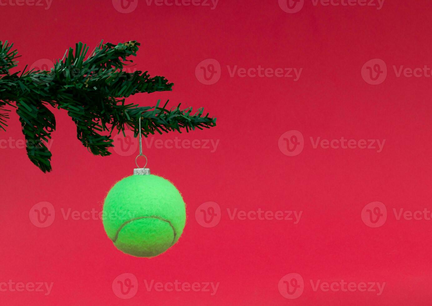 Creative composition of Christmas tree and Christmas bauble made of real tennis ball on red background. Minimal New Year concept. Trendy holiday idea. photo