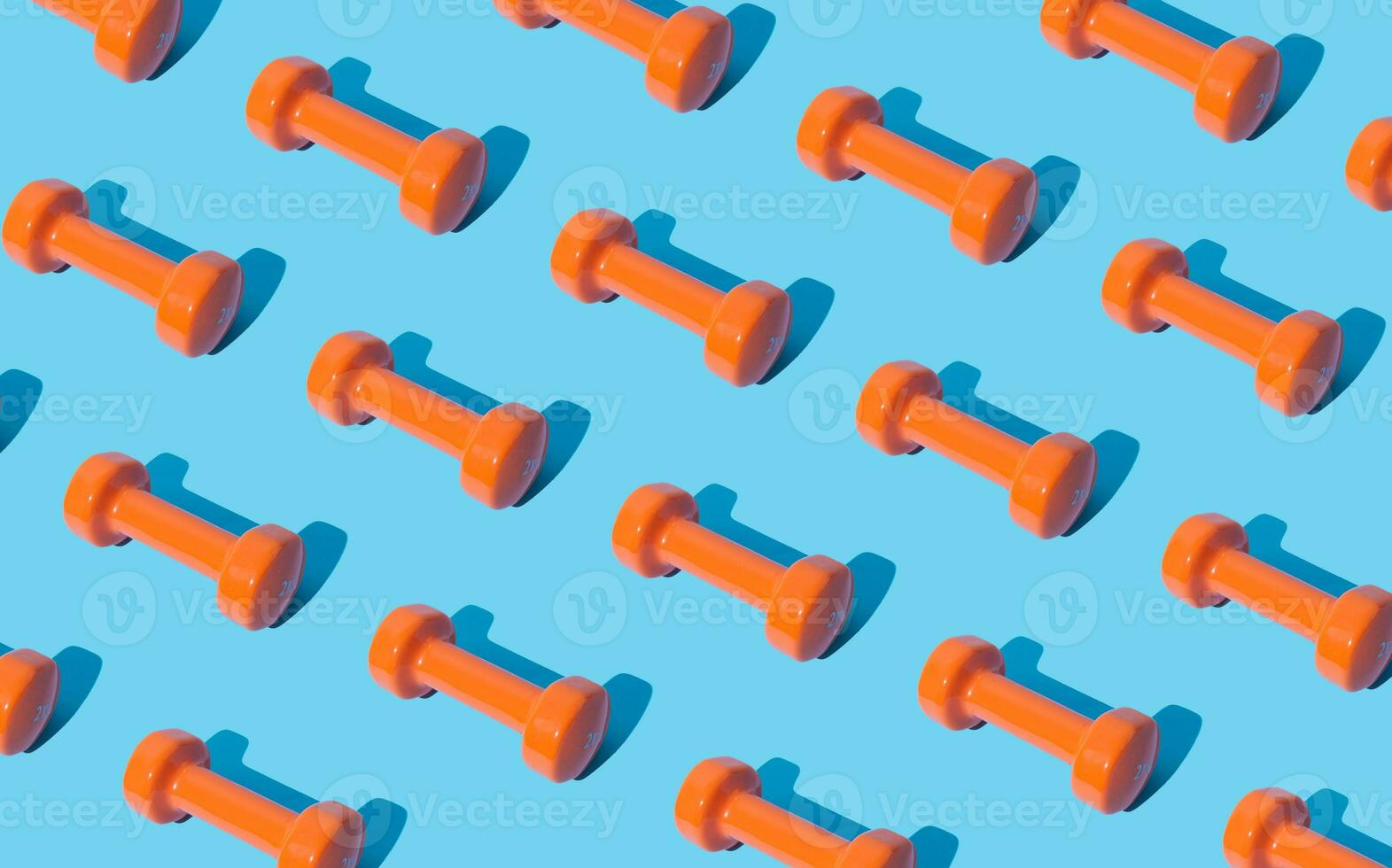 Creative pattern composition made of orange dumbbells on light blue background. Minimal fitness, healthy lifestyle and sport concept. Trendy exercise and fitness backround idea. photo