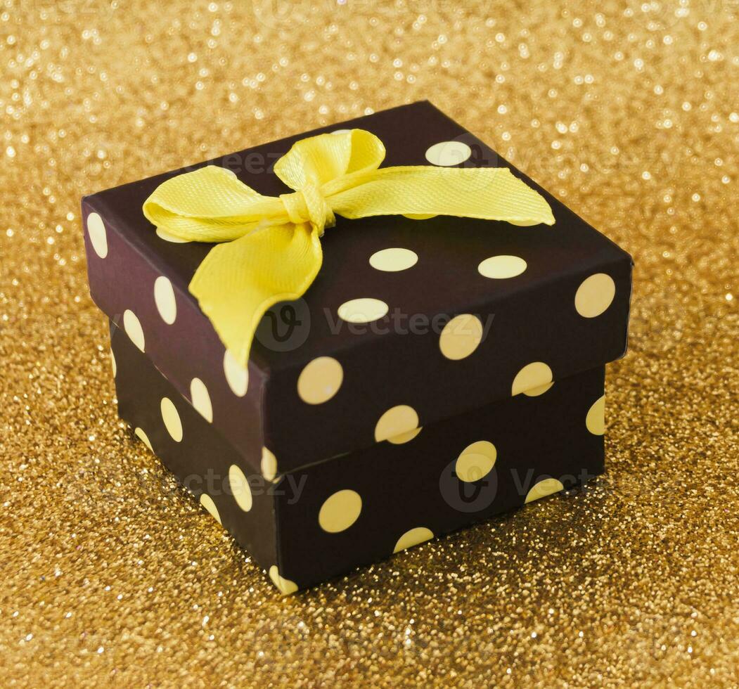 Closeup view minimal composition of Christmas gift box on golden backdrop. New Year present concept background. Trendy gift box idea. Luxury layout. photo