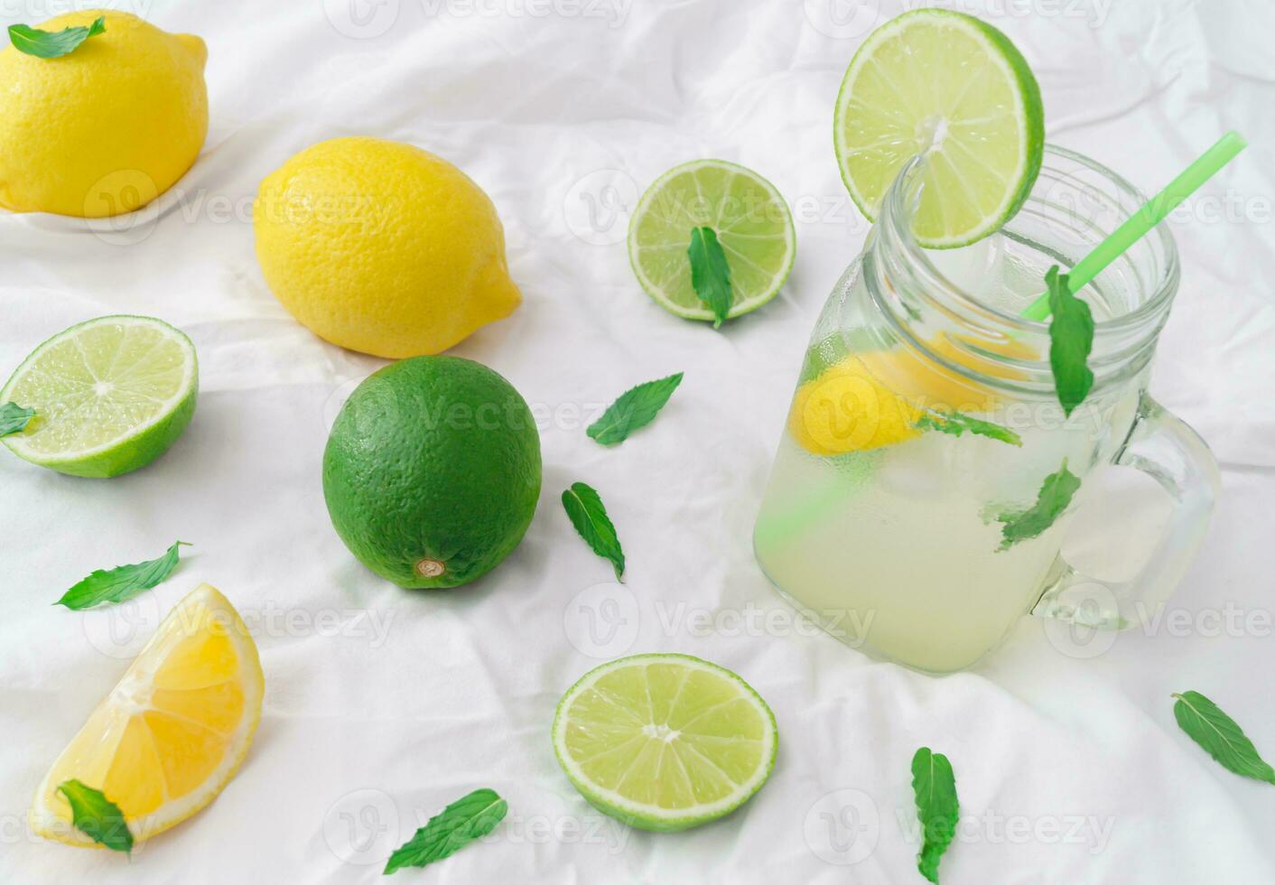 Fresh summer cocktail made of citrus fruit and green mint leaves on white background. Creative tropical lime and lemon concept. Minimal lemonade layout. Exotic summer party background. photo