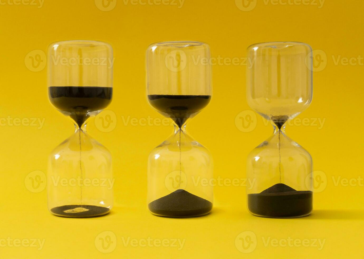 Like sands through the hourglass, so are the days of our lives. Creative hourglass, sandglass, sand timer or sand clock against yellow background concept. Minimal background idea. Hourglass aesthetic. photo