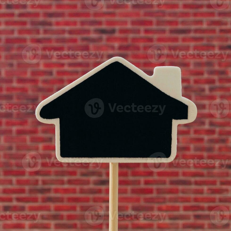 Creative layout made of black writing board in house shape against red brick wall background.  Minimal black writing board concept. Trendy background with copy space idea. photo