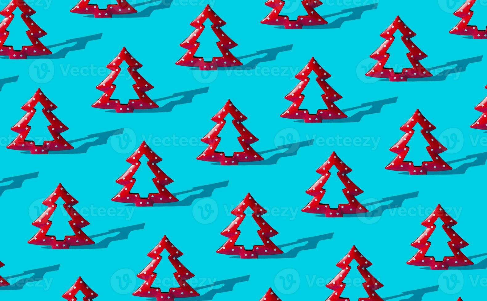 Minimal composition pattern background of red Christmas trees on light blue. New Year or Christmas concept. Trendy winter holidays pattern background idea. photo