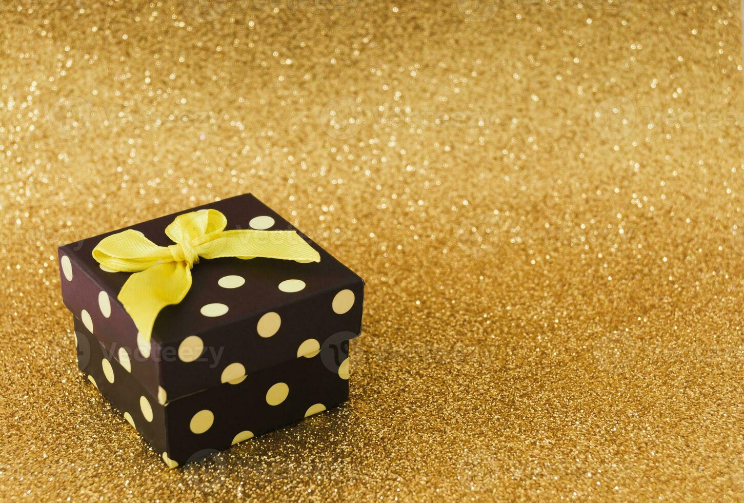 Closeup view minimal composition of Christmas gift box on golden backdrop. New Year present concept background. Trendy gift box idea. Luxury layout with copy space. photo