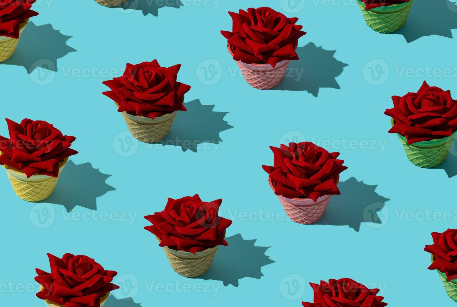 Creative pattern made of red roses in colorful ice cream cones on light blue background. Creative summer pattern concept. Minimal ice cream idea. Trendy red roses composition. photo