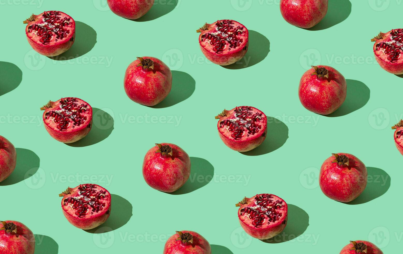 Trendy fruit pattern made of fresh red pomegranates on light pastel green background. Minimal healthy food layout. Nature fruit concept. Pomegranate aesthetic background pattern. photo
