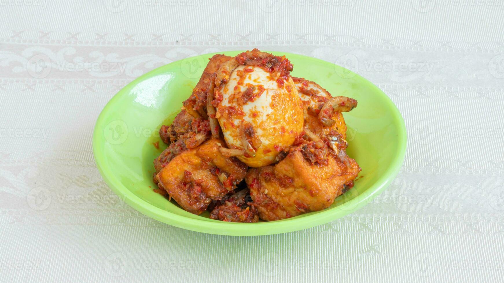 Balado egg sauce, chili sauce filled with eggs, anchovies, and tofu. Served in a bowl on a gray background. Selected focus. photo