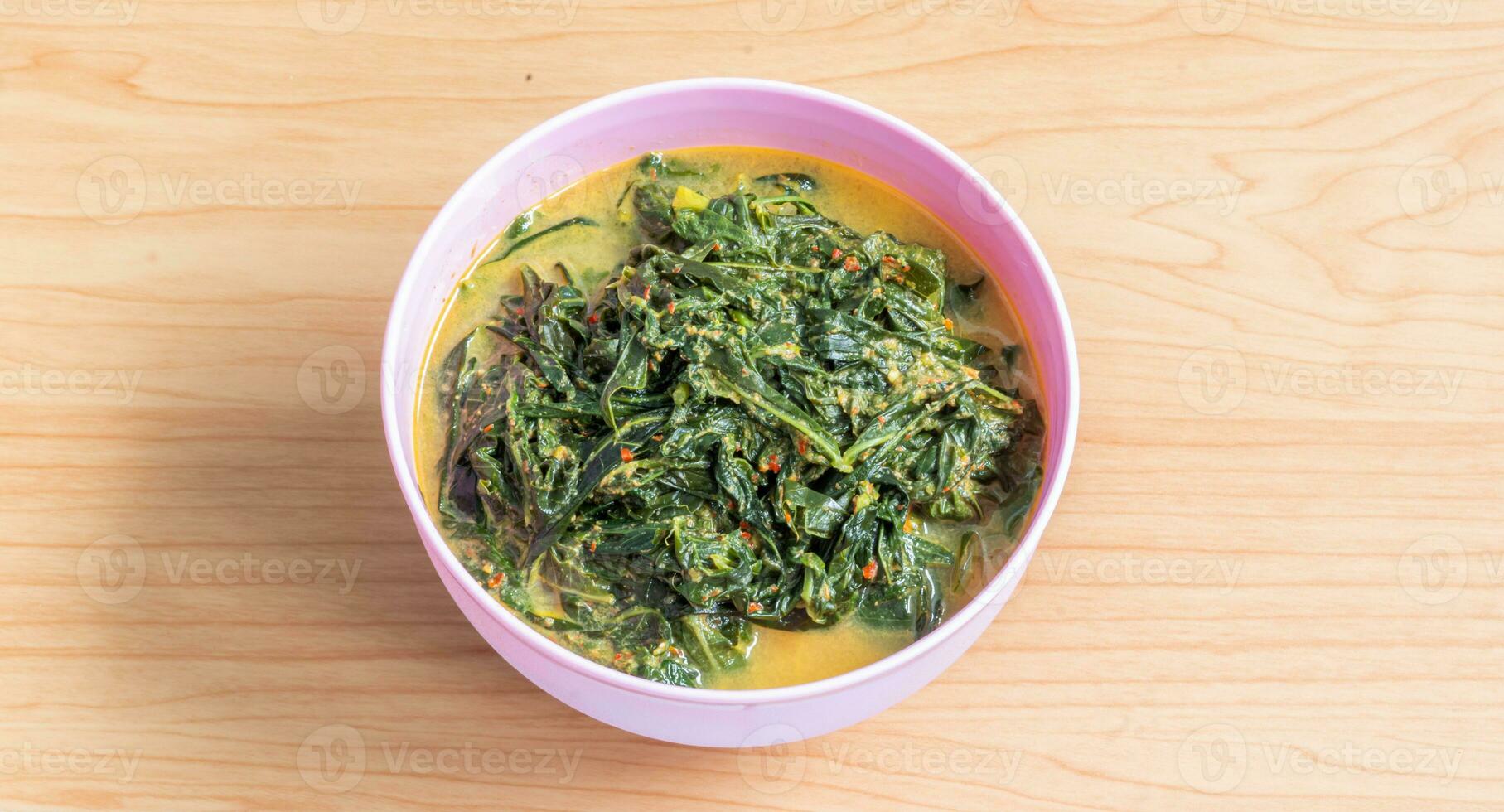 Gulai daun singkong in Minang is indonesian traditional cuisine made from cassava leaves cooked with coconut milk, spices and fried anchovy. Selective focus and blurry selection. photo