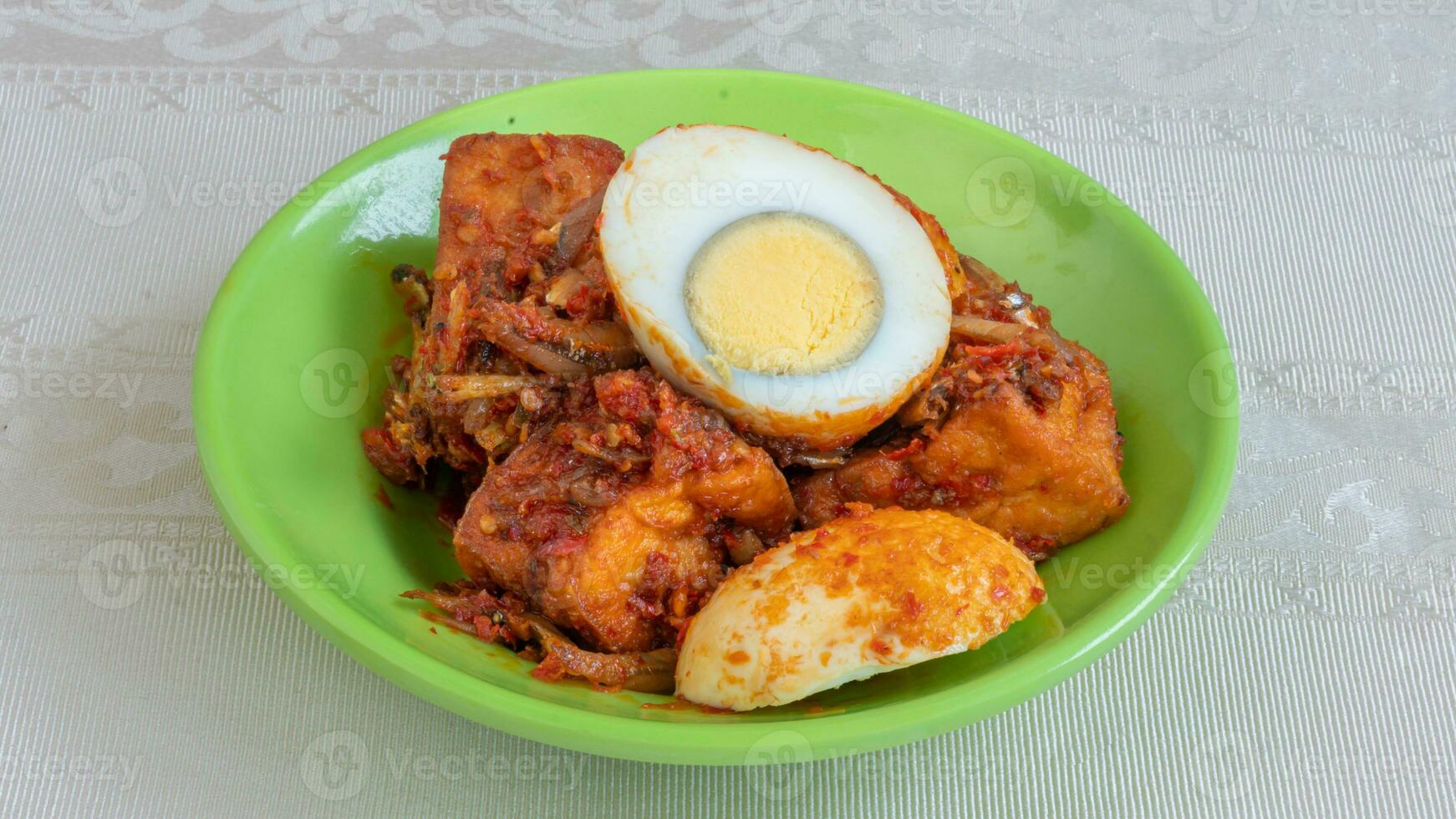 Balado egg sauce, chili sauce filled with eggs, anchovies, and tofu. Served in a bowl on a gray background. Selected focus. photo
