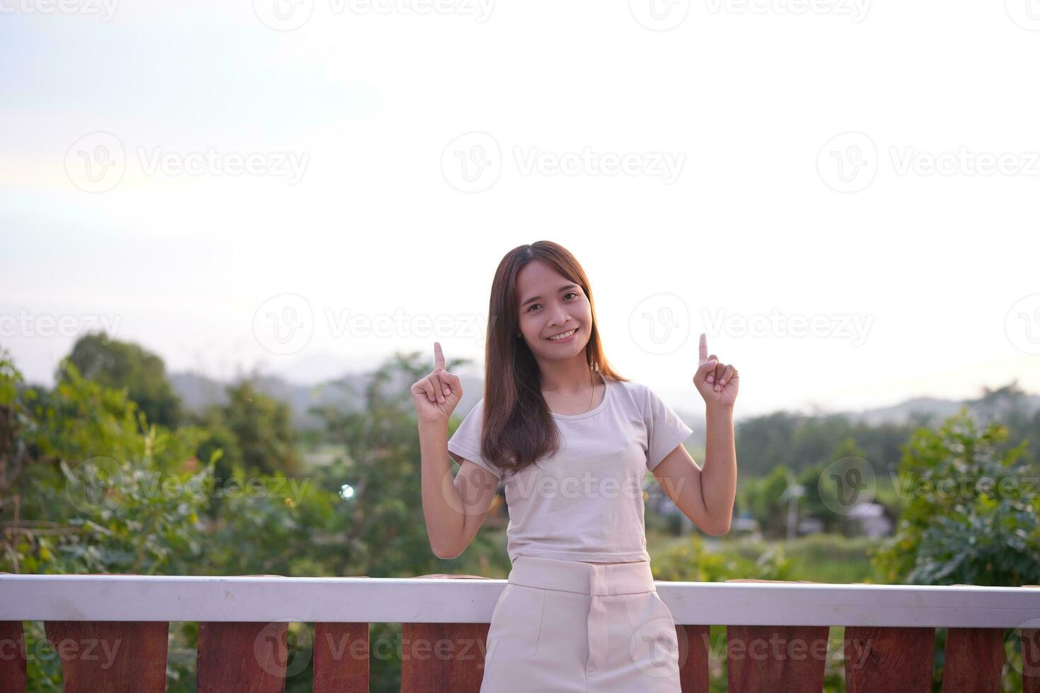 Happy Asian female tourist taking photos on the roof of her accommodation during sunset.