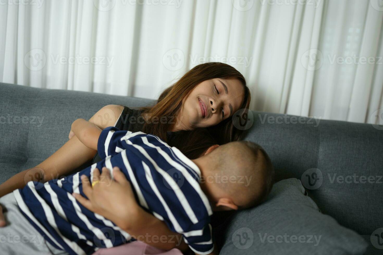 un hijo duerme en su de la madre regazo dentro el casa. foto