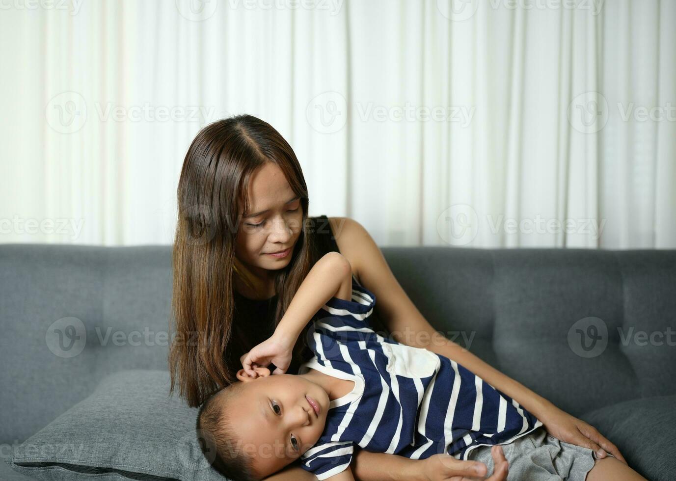 A son sleeps on his mother's lap inside the house. photo
