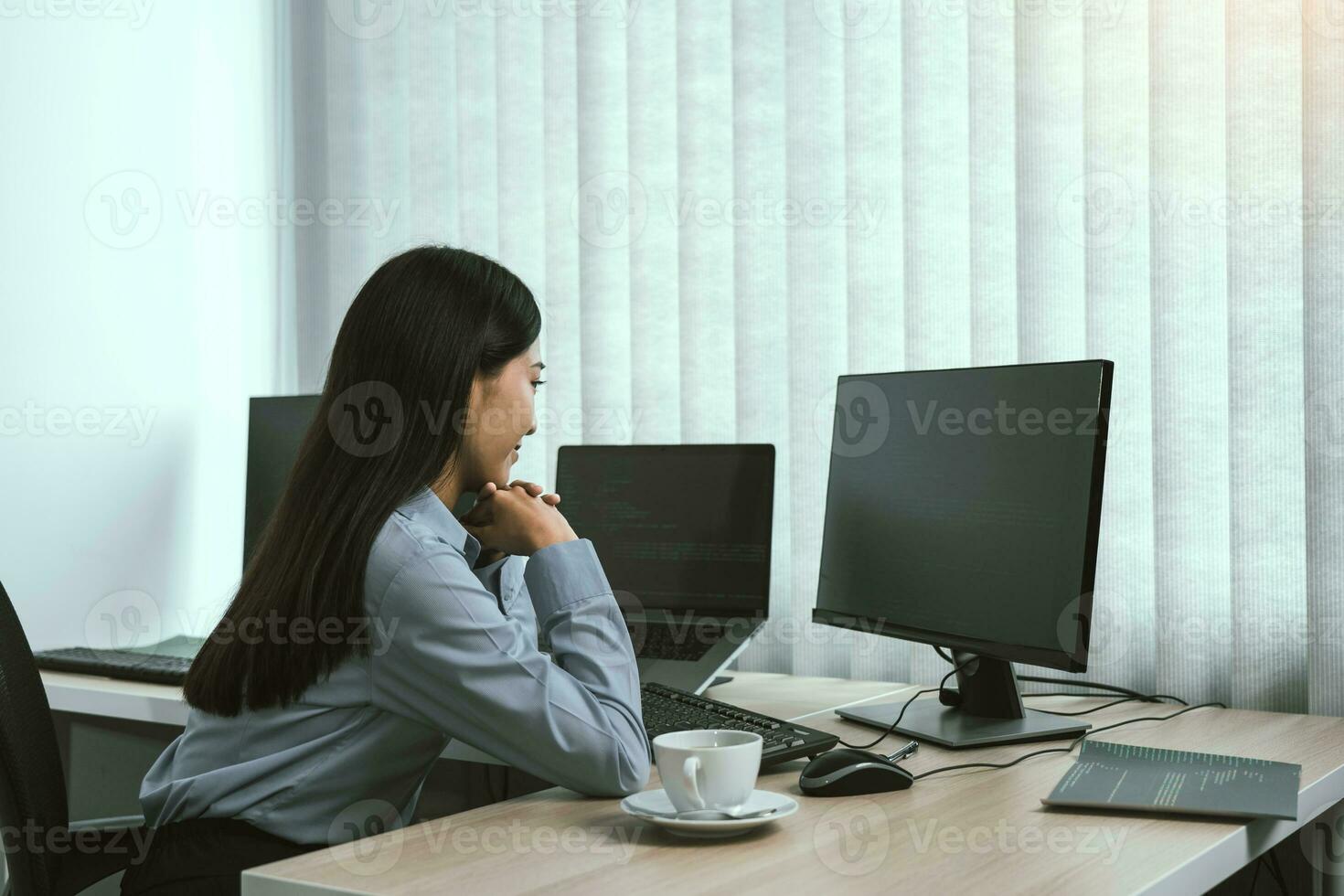 Asian woman software developers sitting in front of computers looking at computer codes on the screen. photo
