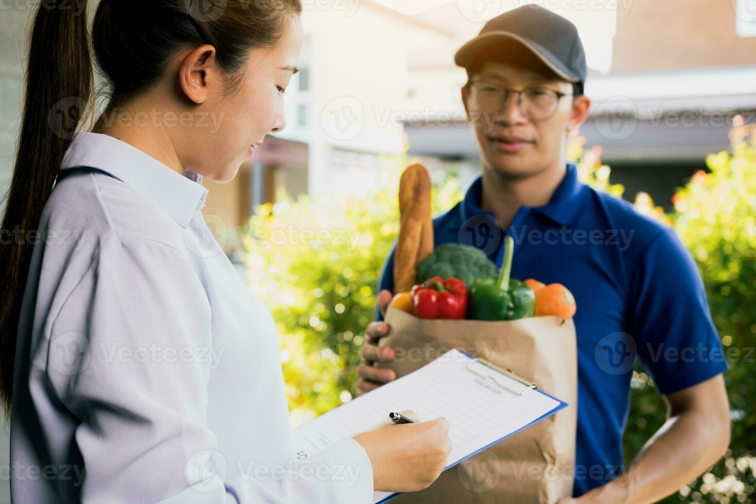 Asian woman is checking the product and signing the receipt on the order receipt through the online supermarket's home store. photo