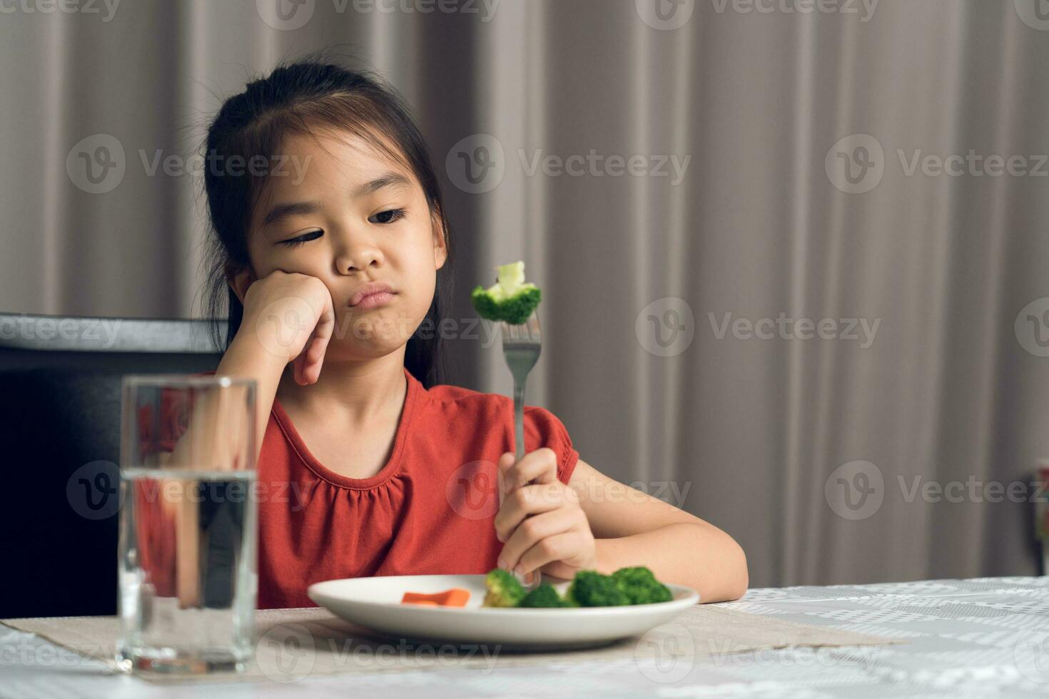 Little cute kid girl refusing to eat healthy vegetables. Children do not like to eat vegetables. photo
