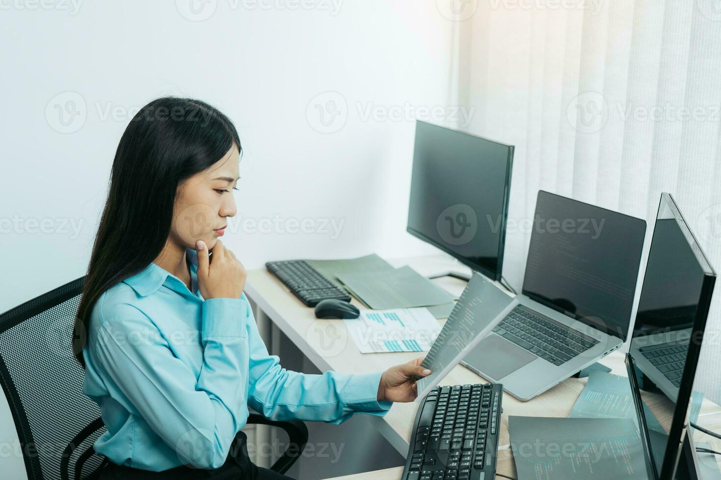 Concentrated asian woman brainstorming while coding data on desktop PC while working on computer codes in the office. photo
