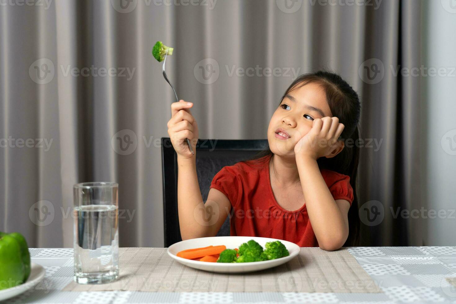 Little cute kid girl refusing to eat healthy vegetables. Children do not like to eat vegetables. photo